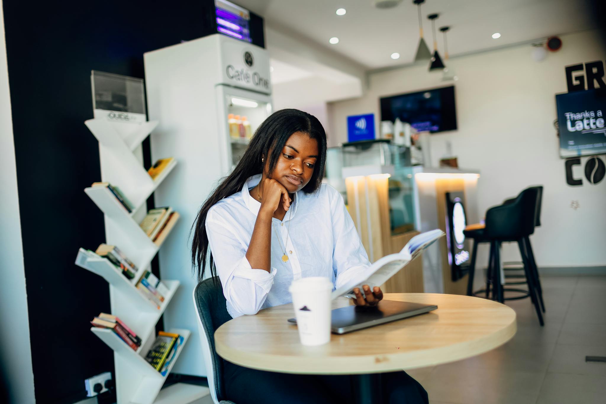 Young woman reading a book in a modern Lagos coffee shop, reflecting a relaxed and stylish atmosphere.